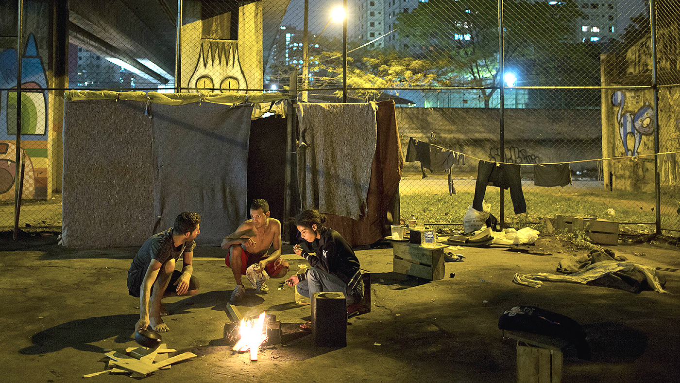 Garotos preparam uma comida em uma fogueira diante do local em que vivem, debaixo de um viaduto em São Paulo (AP Photo/Andre Penner)