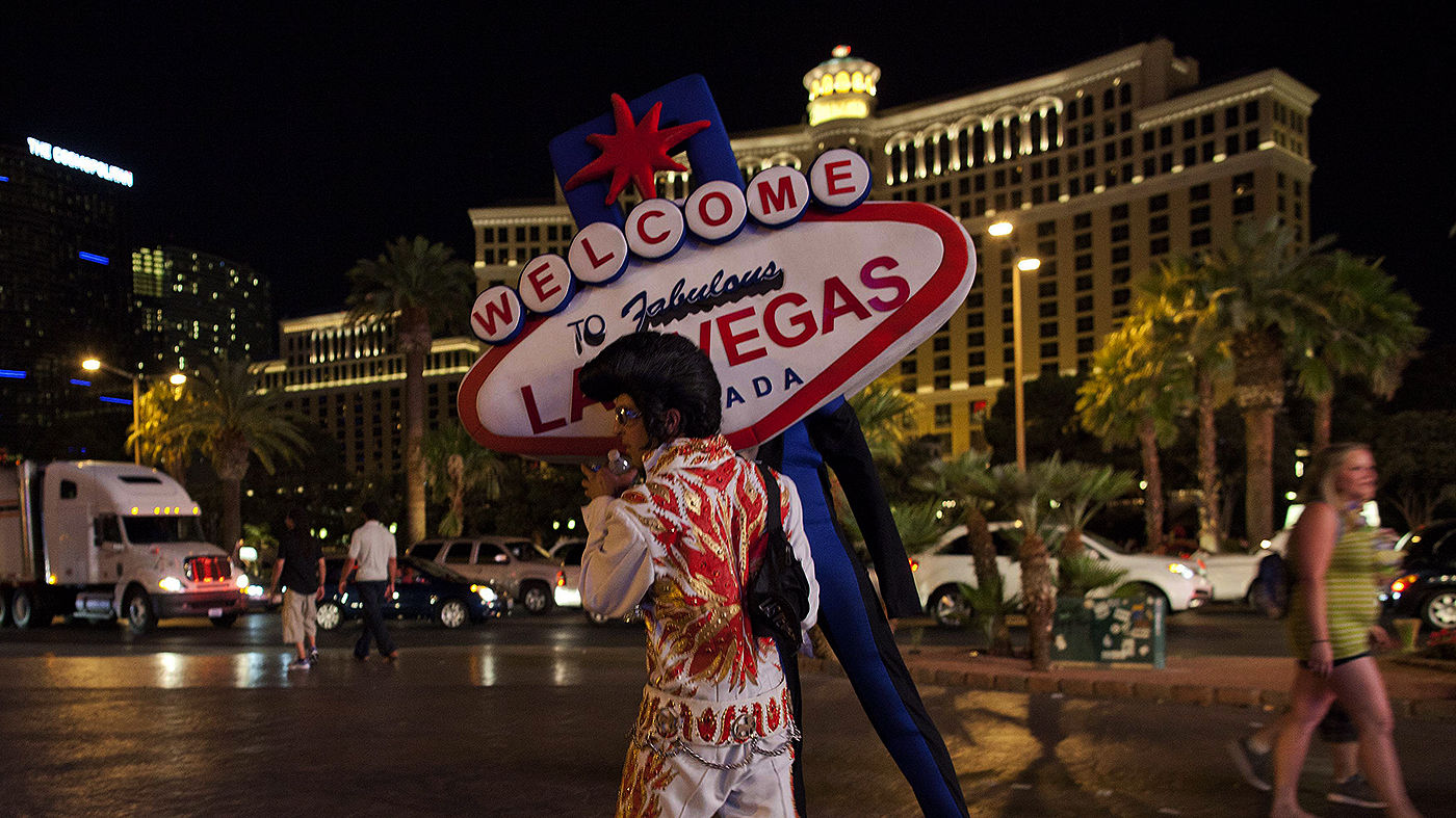 Homem fantasiado de Elvis Presley carrega réplica de placa de Las Vegas (AP Photo/Julie Jacobson)